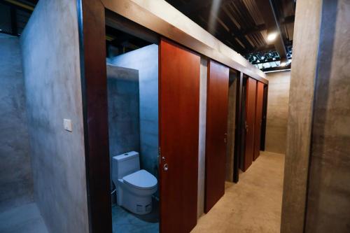a bathroom with a toilet and wooden doors at Tall Tree Kata Phuket in Kata Beach