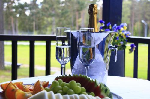 Mullsjö Hotell & Konferens في مولسيو: طاولة مع كأسين من النبيذ وصحن من الفاكهة