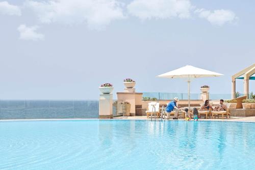 a group of people sitting around a swimming pool at Four Seasons Hotel Alexandria At San Stefano in Alexandria