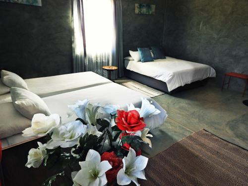 a bedroom with two beds and a vase of white and red flowers at Vastrap Guest Farm in Grünau