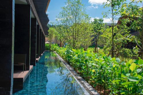a swimming pool in a garden next to a building at Kalima Resort and Villas Khao Lak in Khao Lak