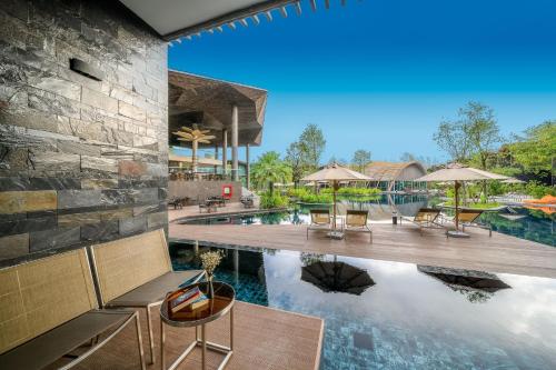 an image of a pool at a resort with chairs and umbrellas at Kalima Resort and Villas Khao Lak - SHA EXTRA PLUS in Khao Lak