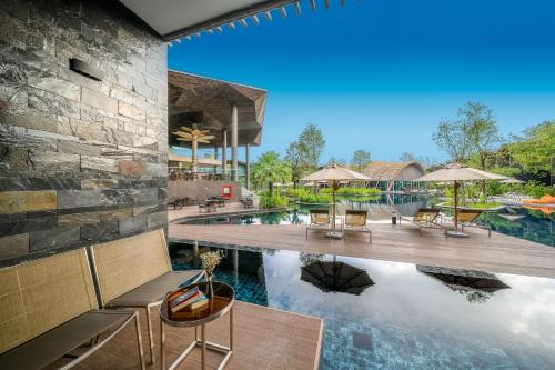 an image of a pool at a resort with chairs and umbrellas at Kalima Resort and Villas Khao Lak in Khao Lak