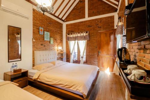 a bedroom with a bed and a brick wall at Omah Teras Bata Guesthouse in Yogyakarta