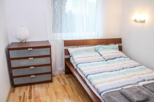 sypialnia z łóżkiem, komodą i oknem w obiekcie Apartament Jasna Plaża w Jastrzębiej Górze