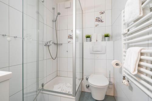 a white bathroom with a shower and a toilet at Nebelhorn Appartementhaus in Oberstdorf