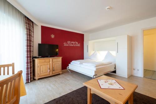 a bedroom with a bed and a tv and a table at Nebelhorn Appartementhaus in Oberstdorf