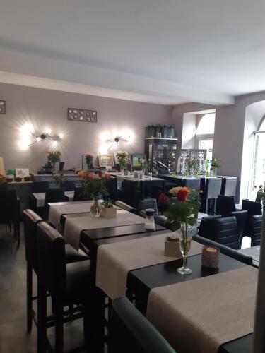 un restaurant avec des tables et des chaises avec des fleurs dessus dans l'établissement Appart'Hôtel Les Tilleuls, à Saint-Macaire