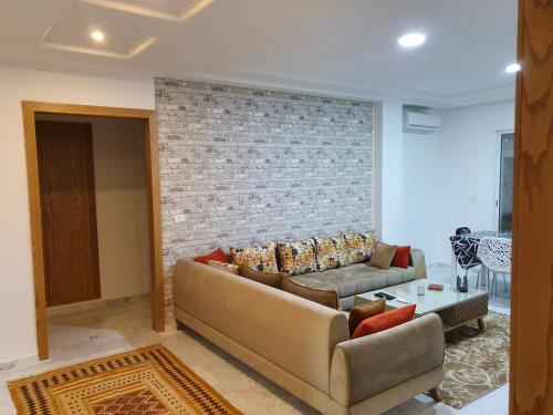 a living room with a couch and a brick wall at Appartement S+1 Jardin De Carthage in Tunis