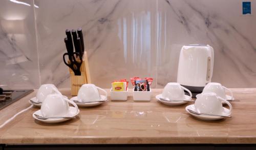 - un comptoir de cuisine avec de la vaisselle et des ustensiles blancs dans l'établissement Samaya Holiday Homes, à Dubaï