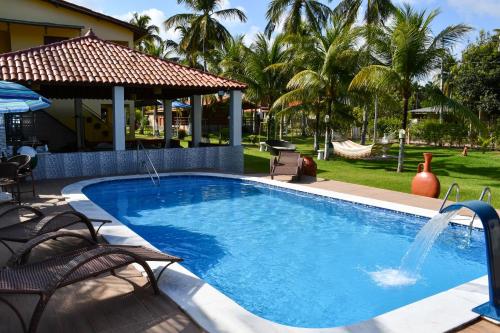 una piscina con 2 sillas y un columpio en Chalés de Peroba, en Maragogi