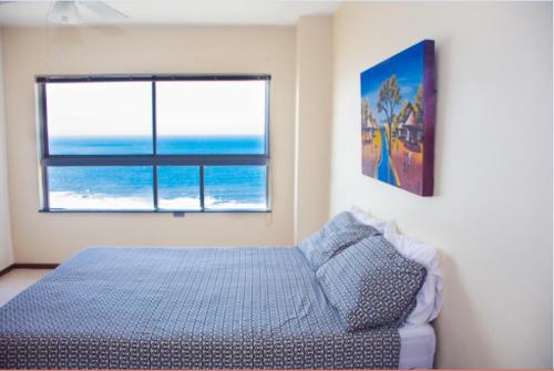 a bedroom with a bed and a view of the ocean at High Tide Beach Condo in Durban