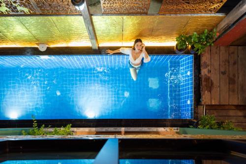 a woman jumping into a swimming pool at Tepbunthom Hostel in Bangkok