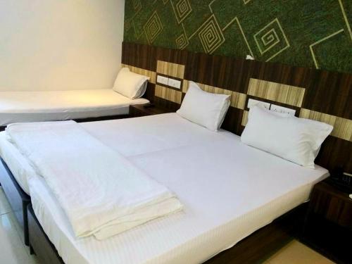 a bedroom with two beds with white sheets at Hotel Shambuji in Thane