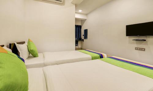 two beds in a room with a tv on the wall at Treebo Arna Residency in Guwahati