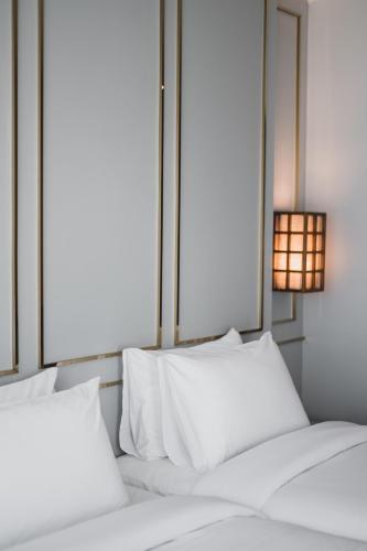 a bed with white pillows and a lamp on it at The Wing Boutique Hotel in Chiang Mai
