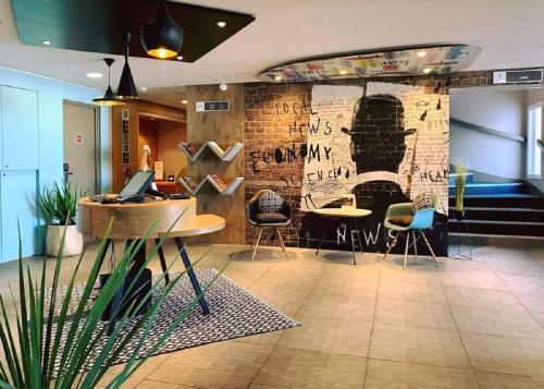 a lobby with tables and chairs and a brick wall at Hotel ibis Narbonne in Narbonne