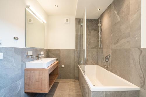 a bathroom with a sink and a bath tub at Wagstätt Residenzen Jochberg by Alpina-Holiday in Jochberg