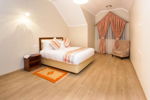 a bedroom with a bed and a chair and a window at Cozy Residences by Trianum in Nairobi
