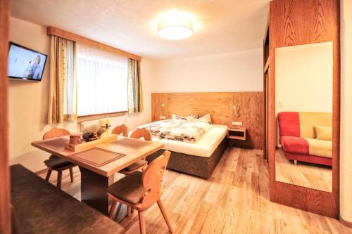 um quarto de hotel com uma cama, uma mesa e cadeiras em Bäckerei Schranz em Sankt Leonhard im Pitztal