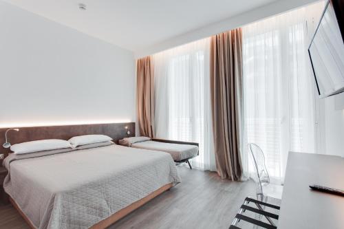 ミラノ・マリッティマにあるHotel Nadirのベッド2台、デスク、窓が備わるホテルルームです。