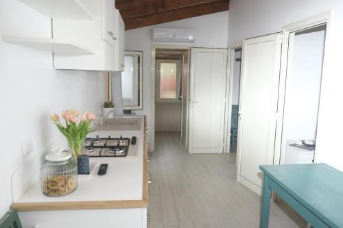 a kitchen with white cabinets and a vase of flowers on a counter at Villaggio Camping Torre Del Porticciolo in Porto Conte