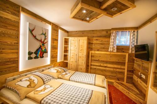 two beds in a room with wooden walls at Villa Salza in Sankt Martin am Grimming