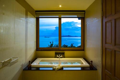 a bath tub in a bathroom with a window at Villa Moonstone in Laem Set Beach