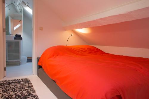 a bedroom with an orange bed in a room at La Garçonnière de Wiertz - Esc'Appart in Dinant