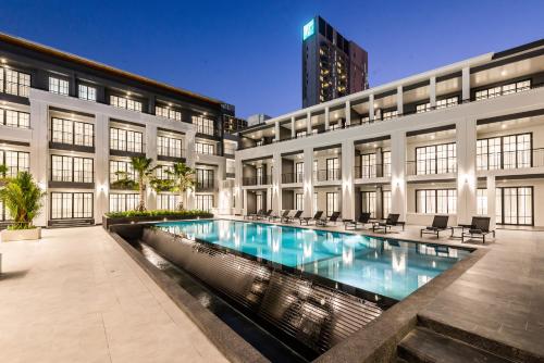 a building with a swimming pool in front of a building at One Patio Hotel Pattaya - SHA Extra Plus in Pattaya