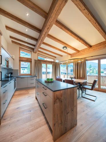a large kitchen with wooden ceilings and a dining room at Wagstätt Residenzen Jochberg by Alpina-Holiday in Jochberg