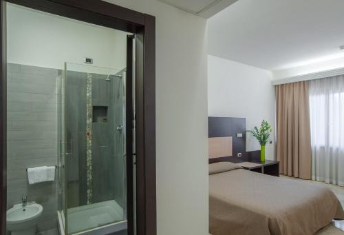 a bedroom with a bed and a shower and a sink at Hotel Boomerang Roma in La Massimina-Casal Lumbroso