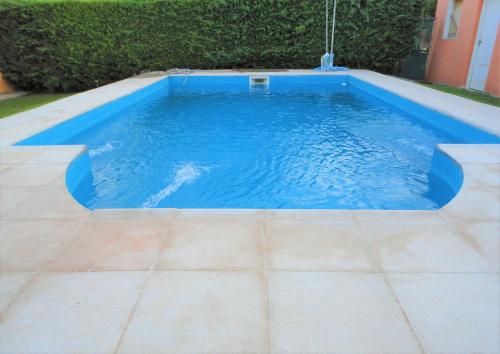 una piscina con suelo de baldosa y agua azul en Jazmin de Lluvia en Vistalba