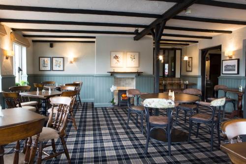 a restaurant with tables and chairs and a fireplace at Gilpin Bridge Inn in Kendal