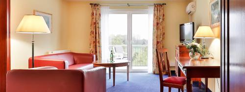 a living room with a chair and a table and a window at Dorint MARC AUREL Spa & Golf Resort in Bad Gögging