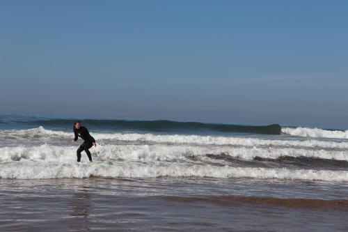 a man riding a wave on a surfboard in the ocean at Pearl Surf Camp Morocco in Agadir
