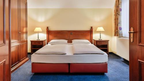 a bedroom with a bed with two night stands and two lamps at Dorint MARC AUREL Spa & Golf Resort in Bad Gögging