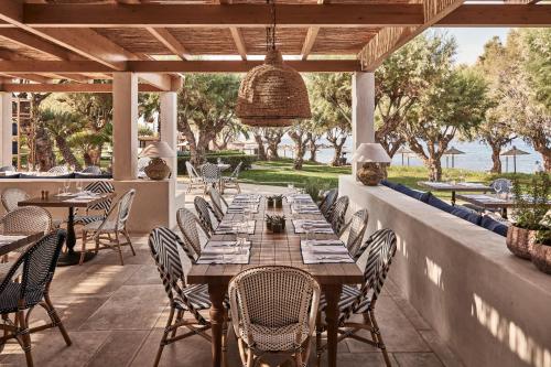 an outdoor dining area with a wooden table and chairs at Phāea Cretan Malia, a Member of Design Hotels in Malia
