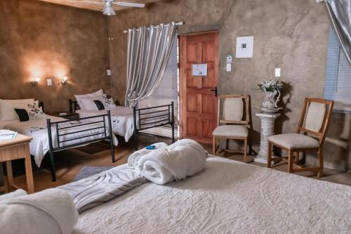a bedroom with two beds and two chairs at Bastille de Blignaut B&B in Edenvale