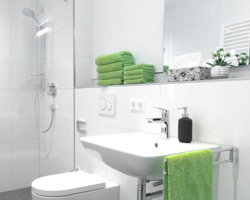 uma casa de banho com um lavatório, um WC e toalhas verdes em Boland Apartments em Rust