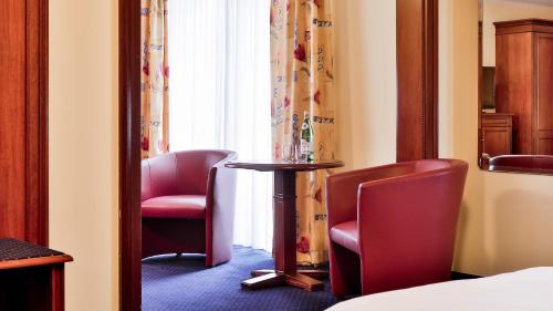 a room with two chairs and a table and a window at Dorint MARC AUREL Spa & Golf Resort in Bad Gögging