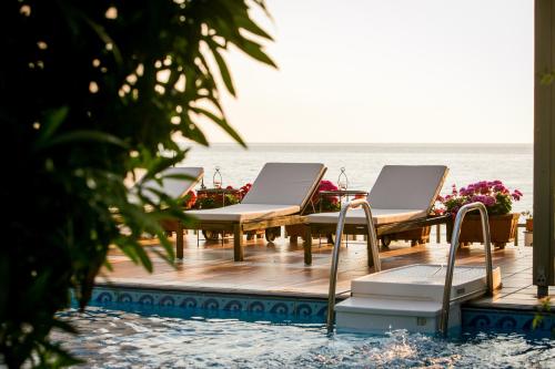 una terraza con sillas y mesas en la playa en Kenta Beach Hotel, en Agios Ioannis