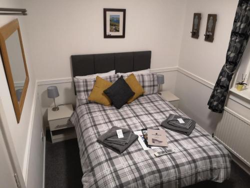 a small bedroom with a bed with a plaid blanket at Gilpin Bridge Inn in Kendal