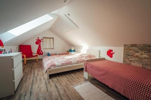 a attic bedroom with two beds and a chair at Apartma BOROVC in Mojstrana