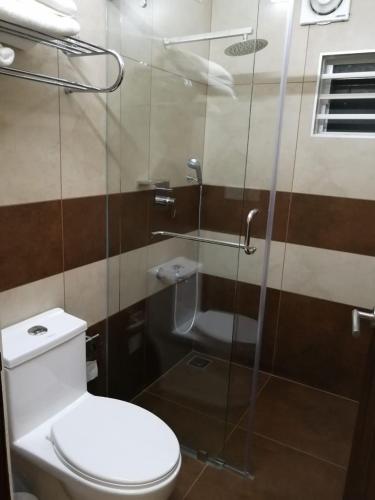 a bathroom with a toilet and a glass shower at Eden Isle Luxury Service Apartment in Cochin