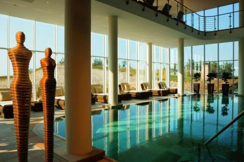 a hotel lobby with a swimming pool and chairs at Ferienhäuser Dünenmeer in Dierhagen