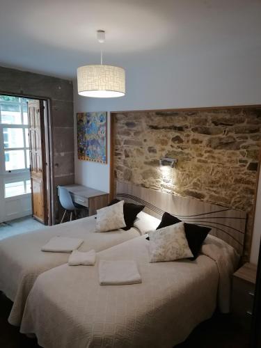 a bedroom with two beds and a stone wall at Hostal Forest in Santiago de Compostela