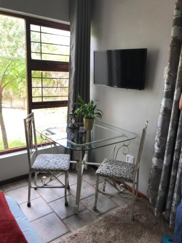 a glass table with two chairs and a television on a wall at Cul de Sac - Accommodation in George