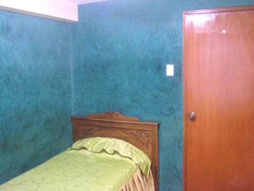 1 dormitorio azul con 1 cama y puerta de madera en Hospedaje Pumacurco Betty, en Cusco