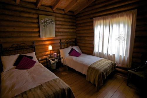 1 dormitorio con 2 camas en una cabaña de madera en Complejo Rural Puerto Peñas, en Aroche